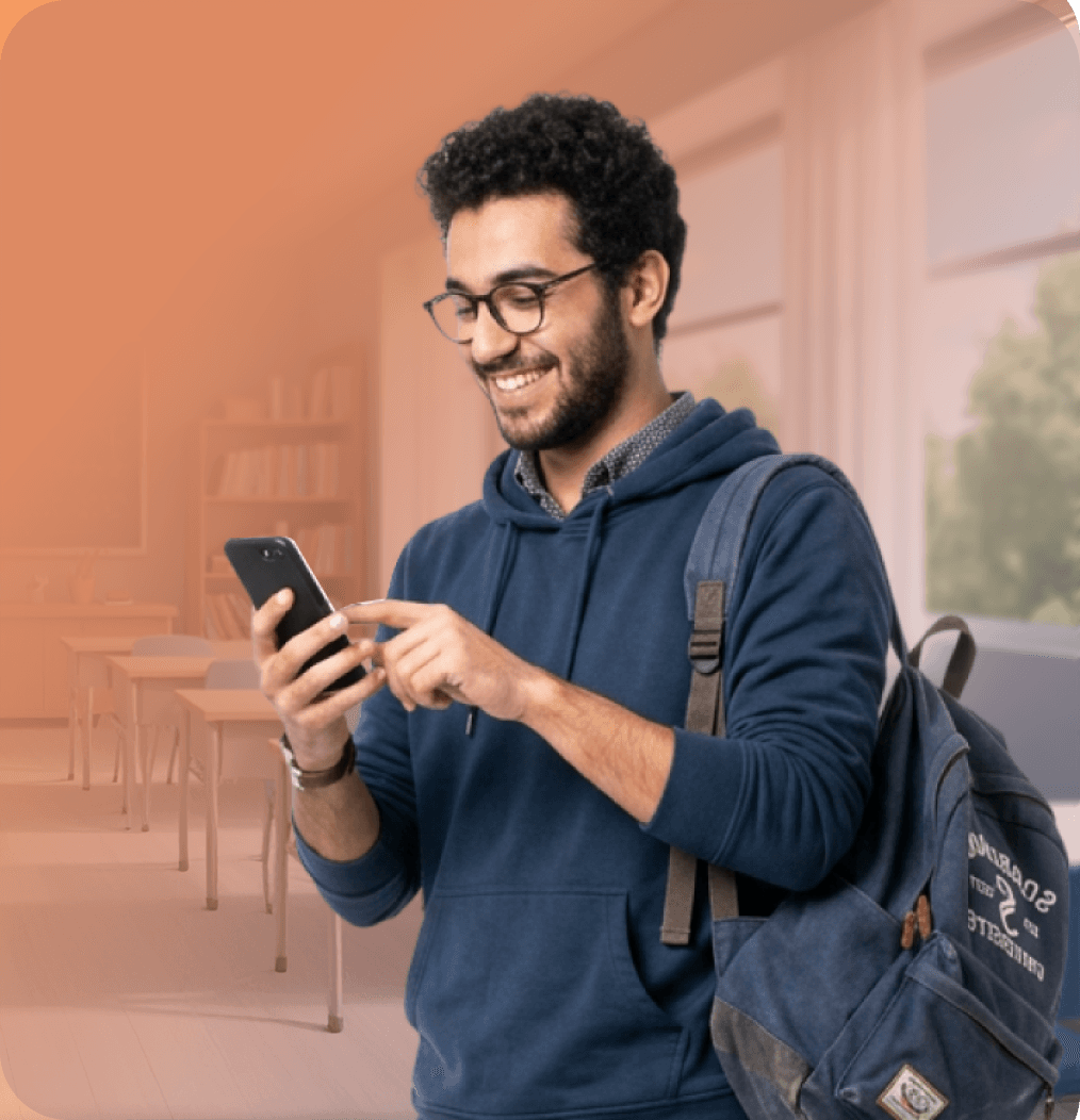 Apprenant souriant devant son téléphone dans une salle de classe